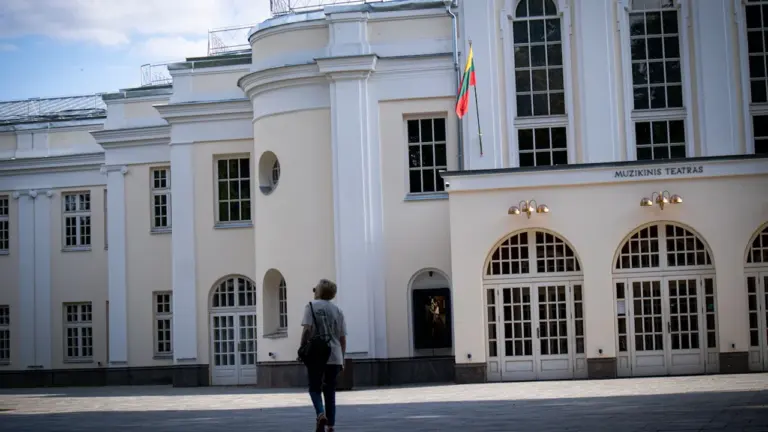 Lankytojas prie Kauno valstybinio muzikinio teatro pastato saulėtą dieną.