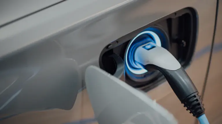 Elektromobilio įkrovimo laidas prijungtas prie automobilio įkrovimo lizdo uždaroje stotelėje.