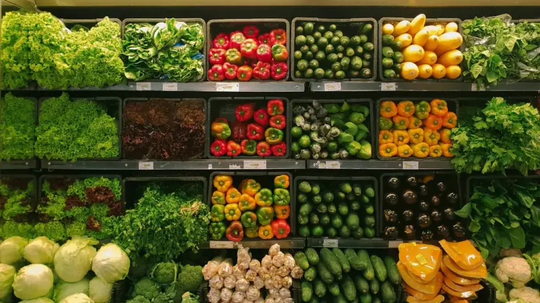 Šviežios daržovės maisto prekių parduotuvės lentynose, iliustruojančios maisto produktų kainų augimą.