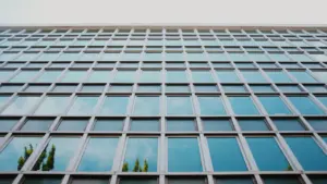 Šiuolaikinis stiklinis administracinis pastatas simbolizuojantis valstybinę instituciją ir skaidrią veiklą.