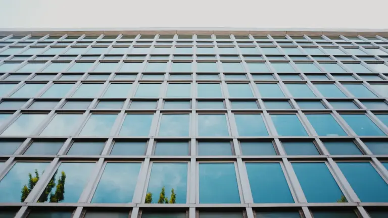 Šiuolaikinis stiklinis administracinis pastatas simbolizuojantis valstybinę instituciją ir skaidrią veiklą.