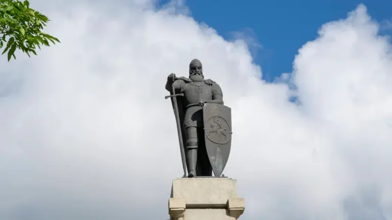 Istorinė paminklo statula su skydu ir kalaviju, simbolizuojanti Lietuvos kovas ir valstybingumą.