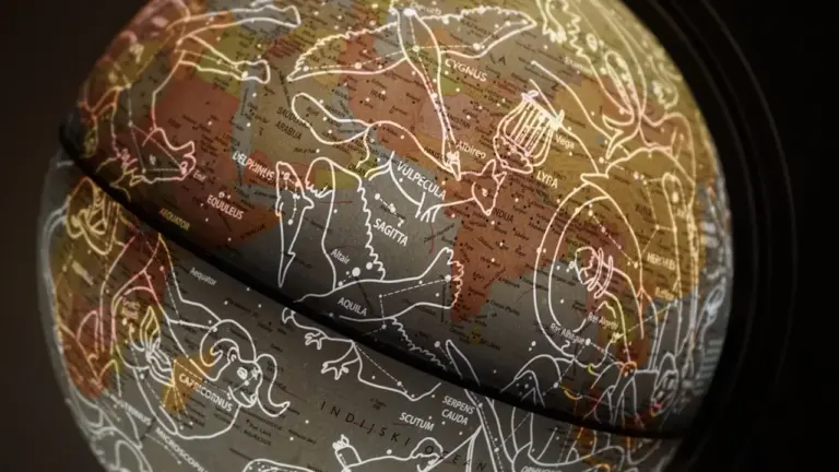 Tamsus gaublys su žvaigždynų žemėlapiu, simbolizuojantis astrologines tendencijas ir susikaupimą.
