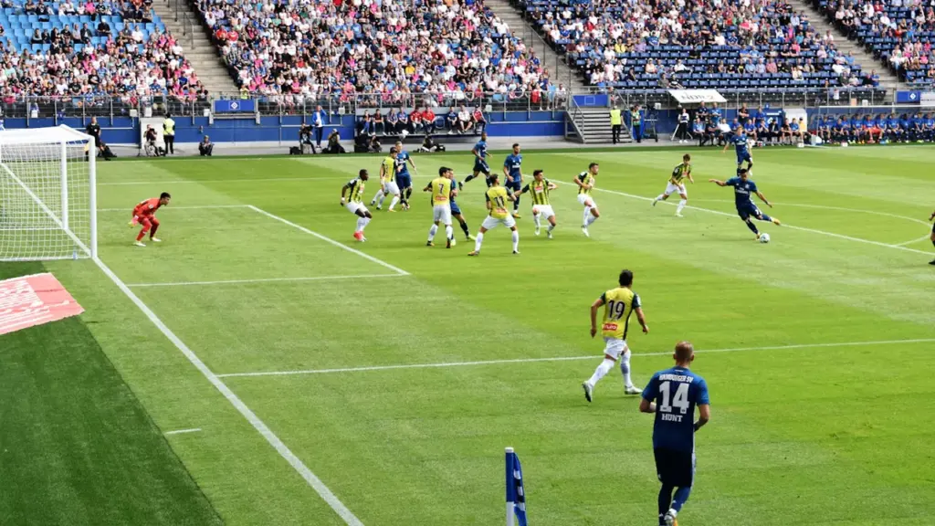Futbolo varžybos pilname stadione su žaidėjais aikštėje prieš svarbų A lygos mačą.