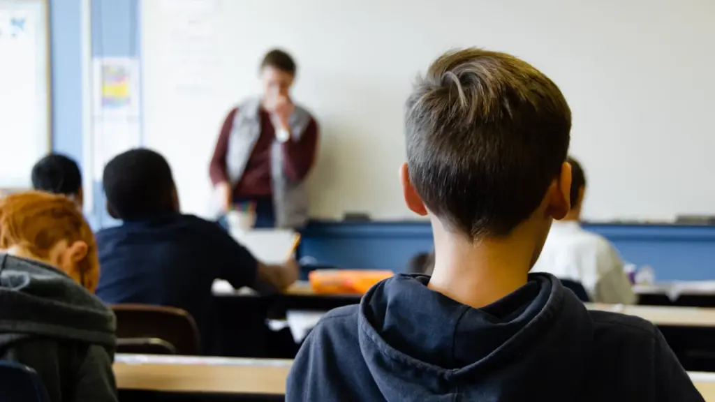 Moksleiviai klasėje klausosi mokytojo per taikos dienai skirtą pamoką mokykloje.
