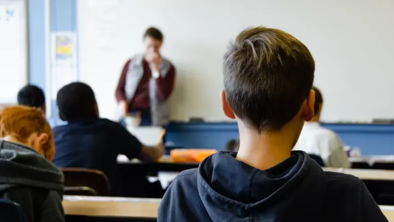 Moksleiviai klasėje klausosi mokytojo per taikos dienai skirtą pamoką mokykloje.